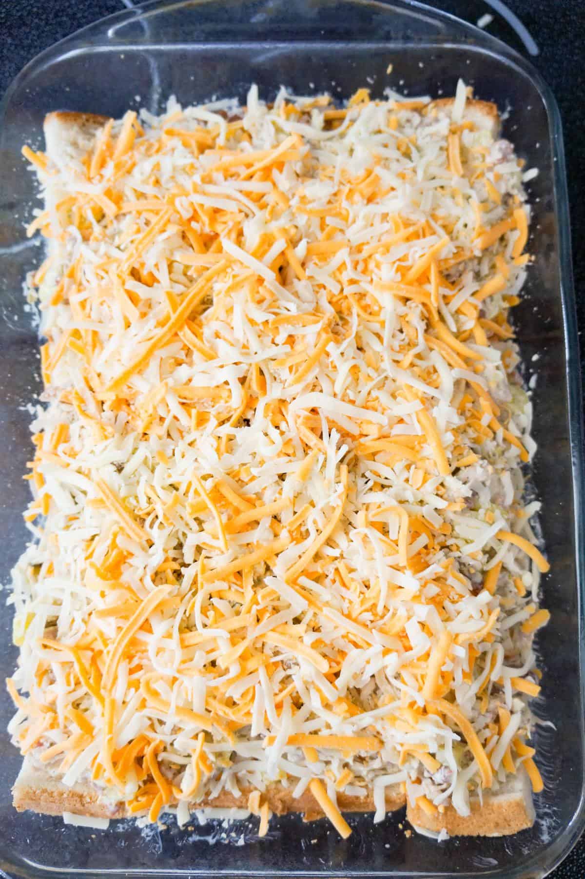 shredded cheese on top of chicken mixture in a baking dish
