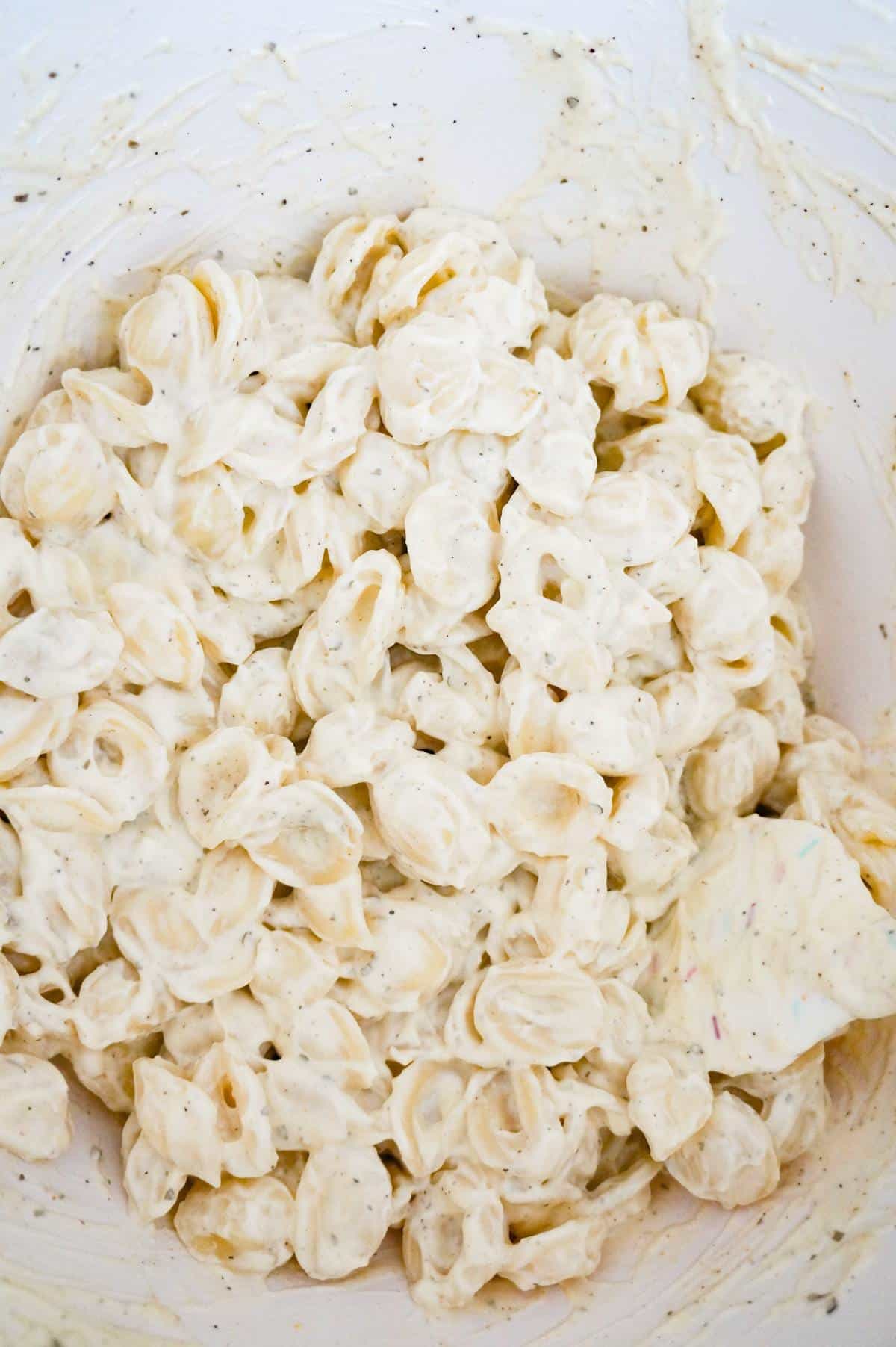 noodles coated in mayo and ranch dressing in a mixing bowl