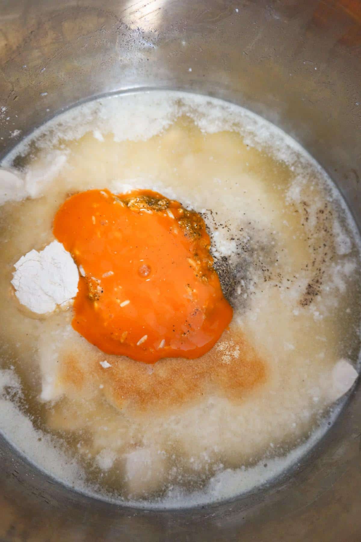 buffalo sauce and spices on top of chicken broth, chicken and rice in an Instant Pot