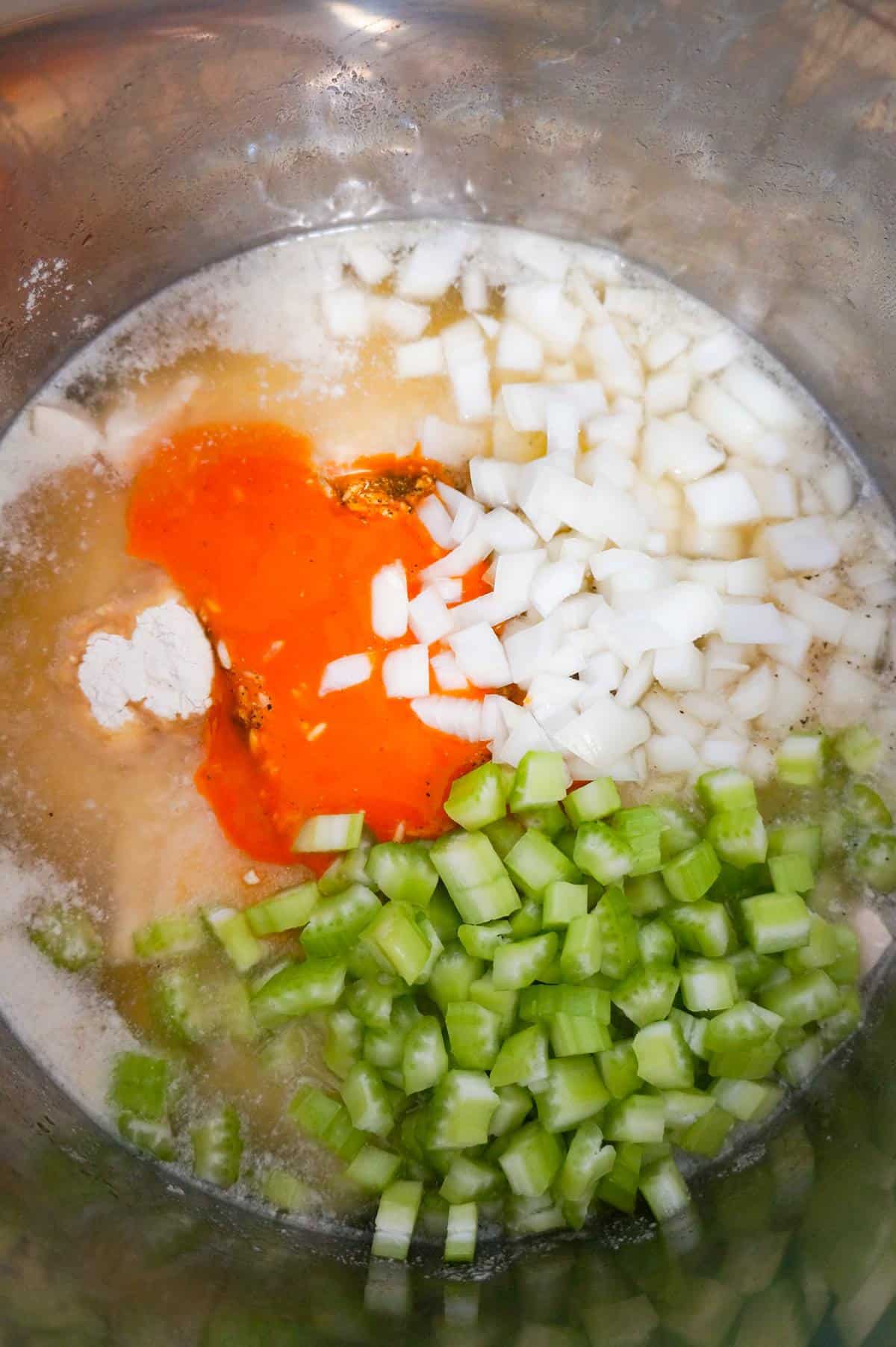 diced celery, diced onions and buffalo sauce on top of chicken and rice in an Instant Pot