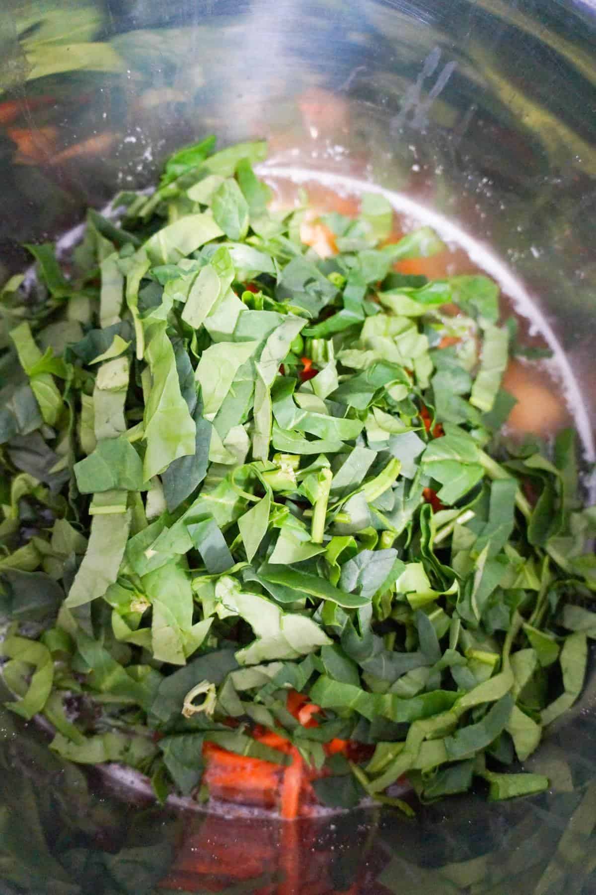 shredded spinach on top of soup ingredients in an Instant Pot