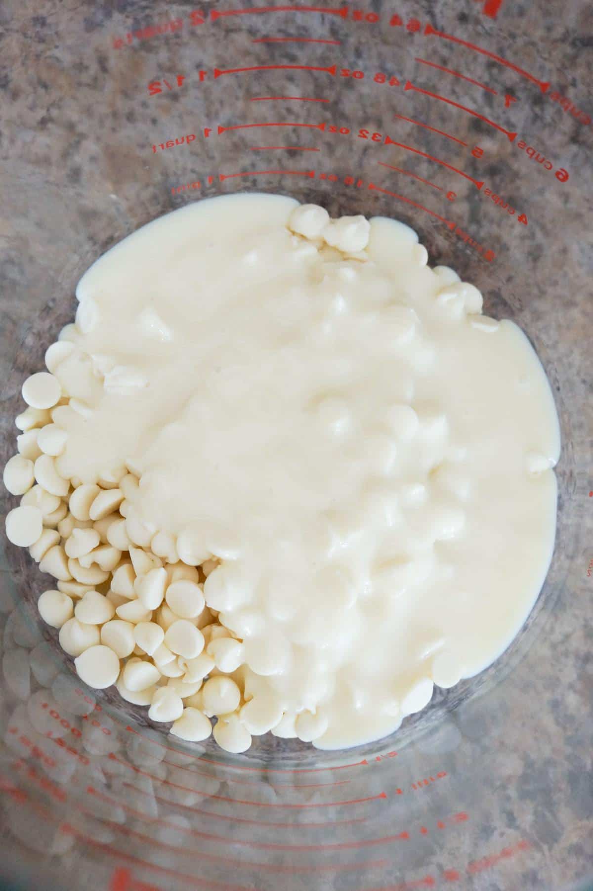 sweetened condensed milk and white chocolate chips in a glass bowl