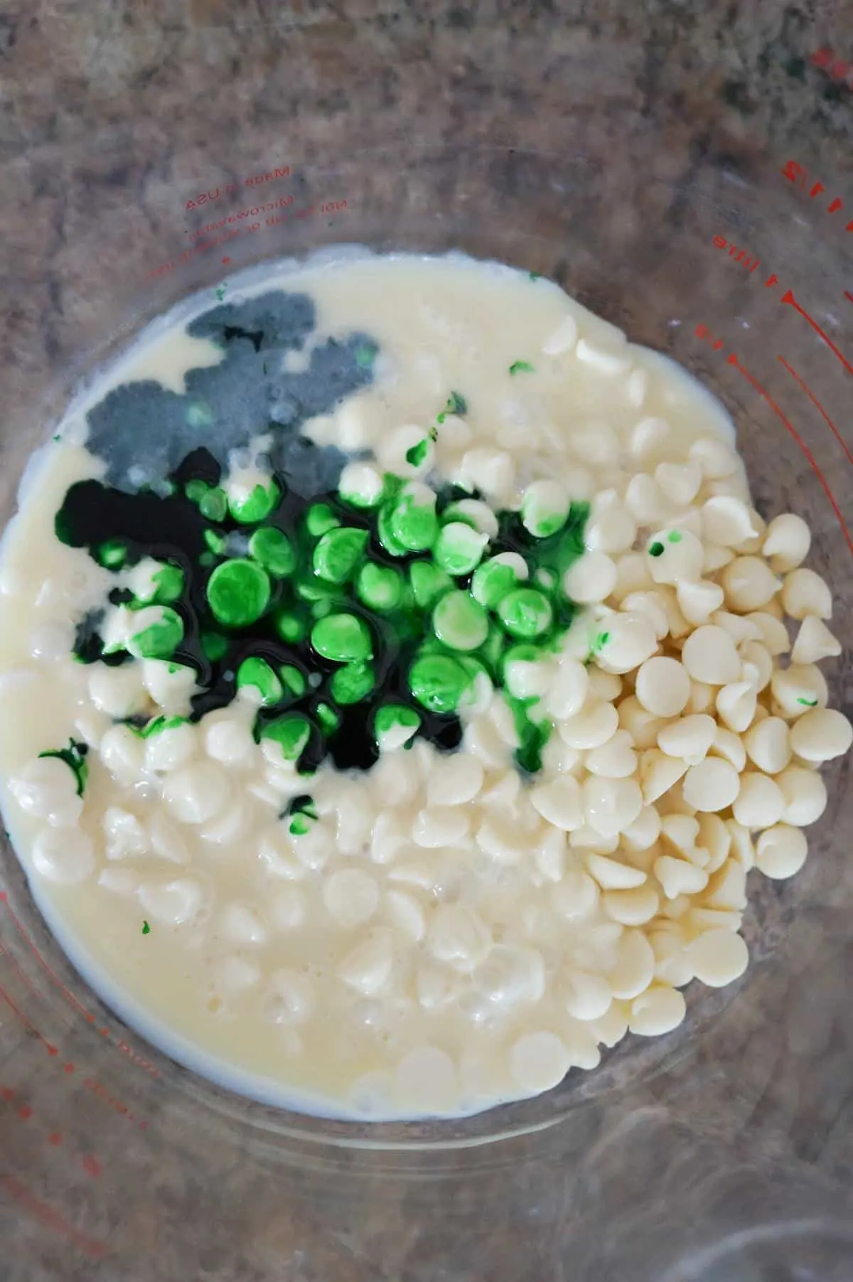 green food colouring, white chocolate chips and sweetened condensed milk in a glass bowl