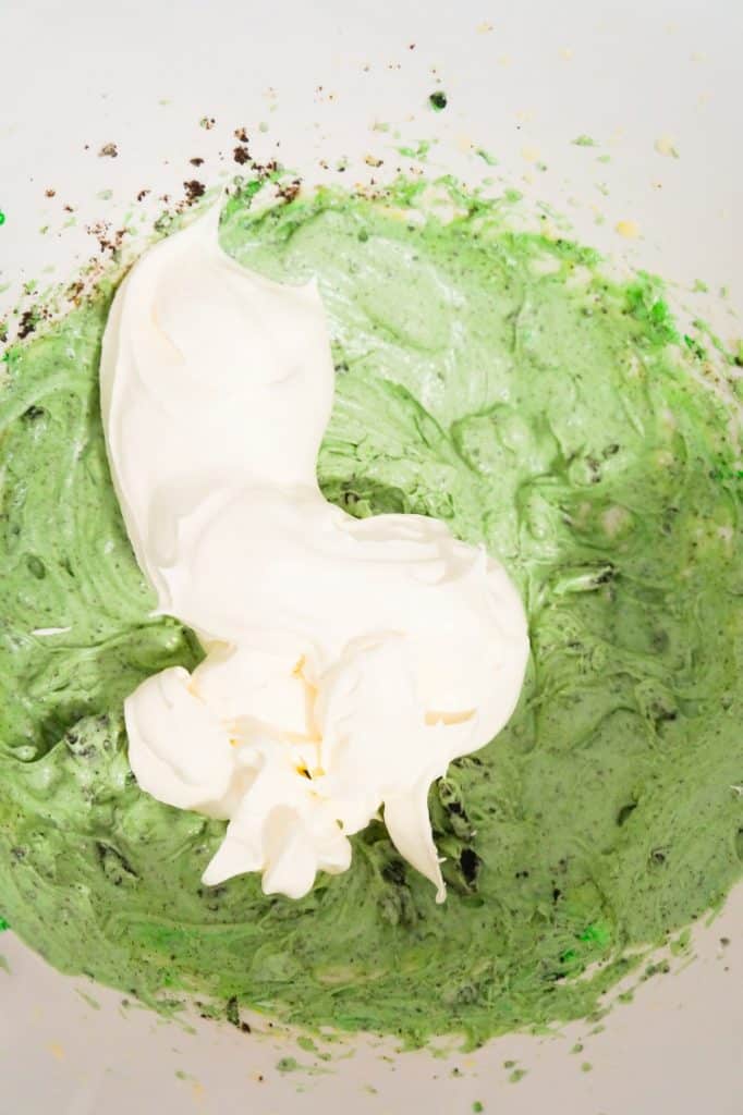 cool whip on top of mint pudding mixture in a mixing bowl