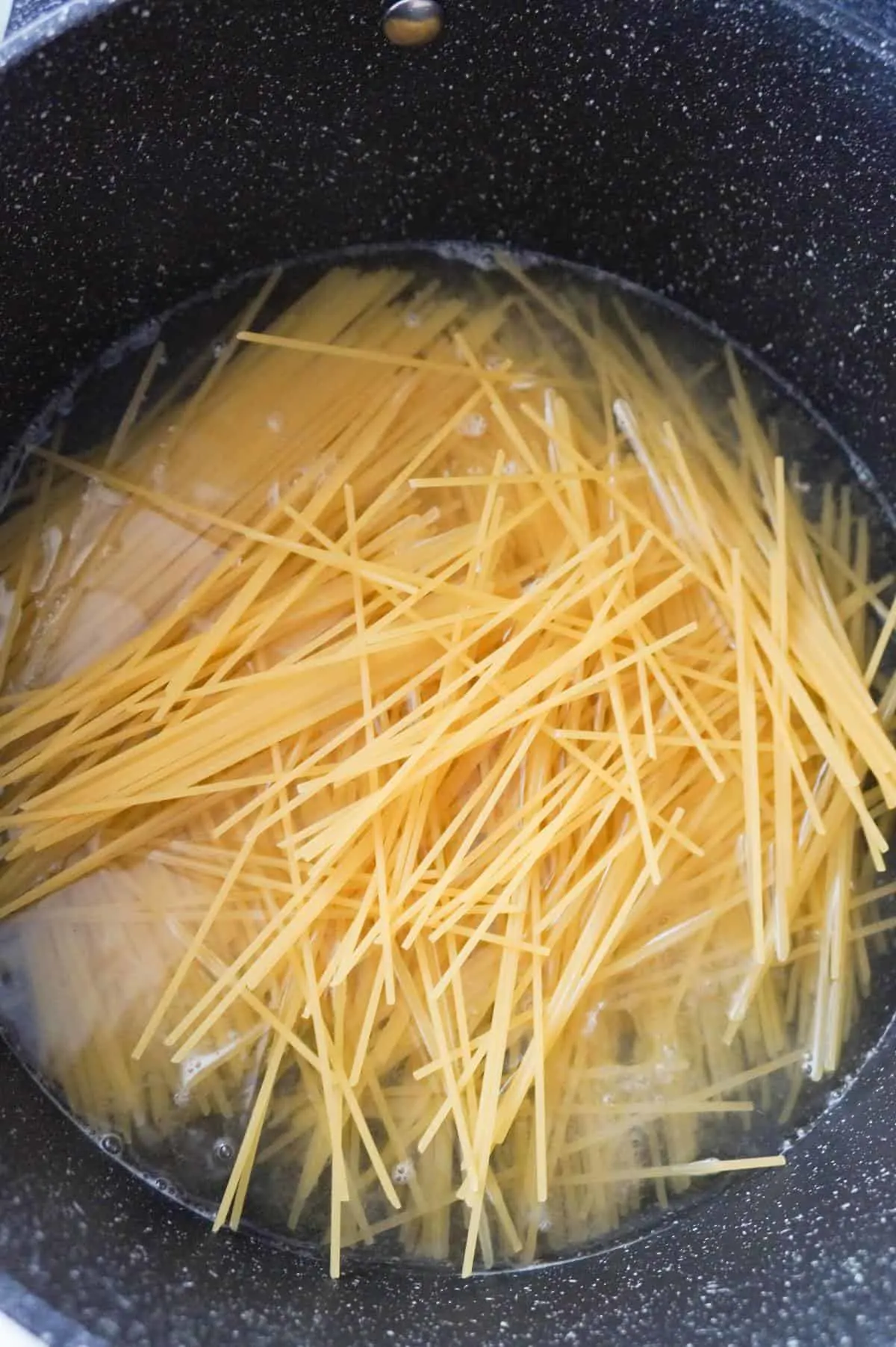 uncooked spaghetti noodles in water in a pot