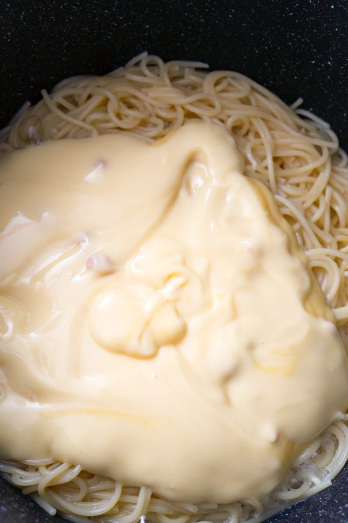 condensed cream of chicken soup on top of spaghetti in a pot