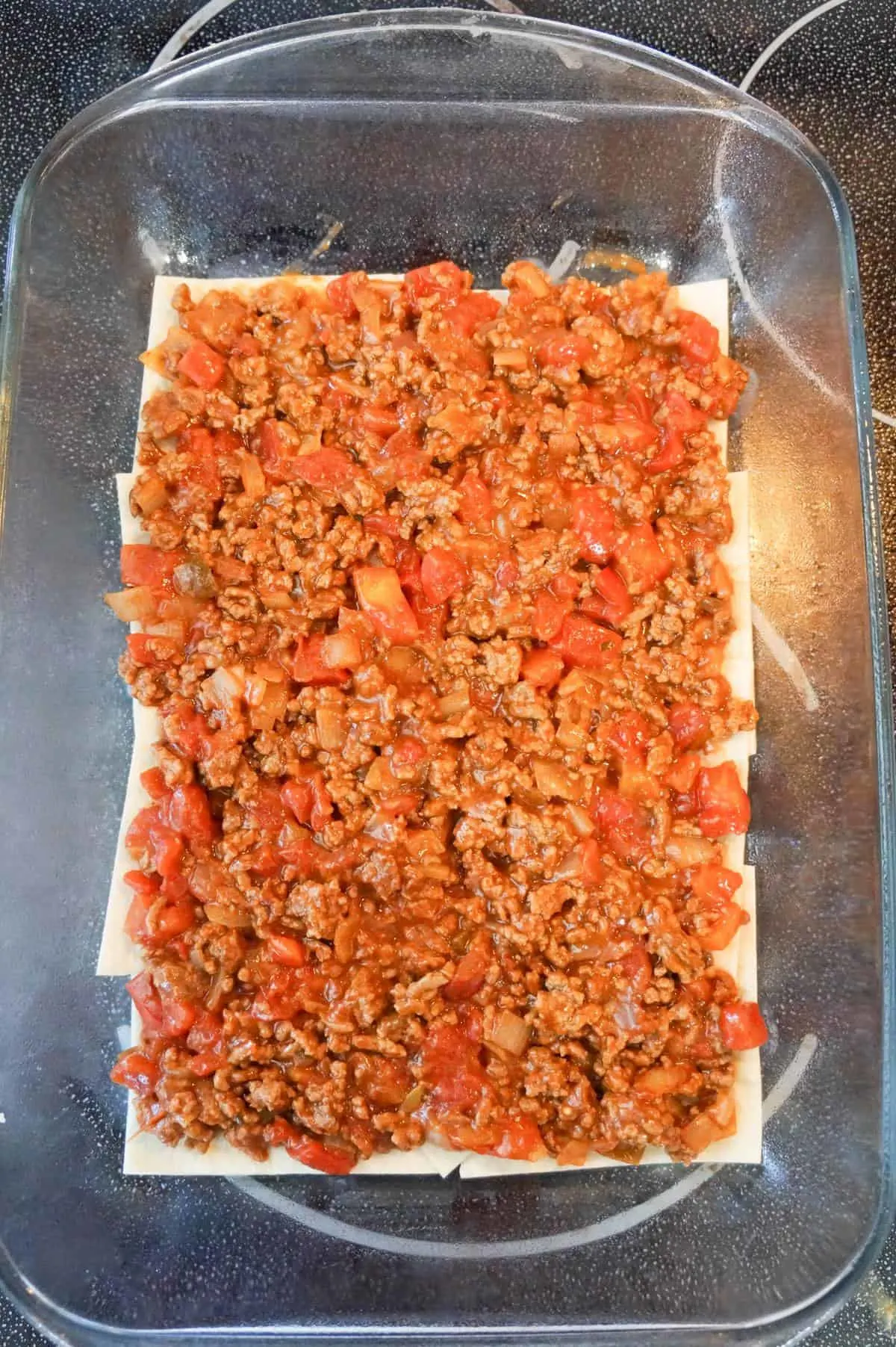 ground beef, salsa and Rotel mixture on top of flour tortilla pieces in a baking dish