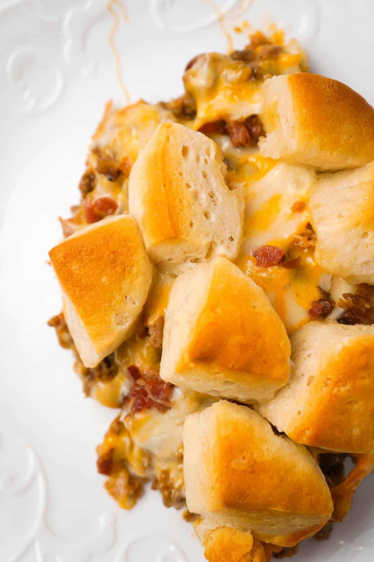 Bacon Cheeseburger Biscuit Casserole is an easy ground beef dinner recipe loaded with diced onions, condensed cheddar cheese soup, ketchup, mustard, crumbled bacon and shredded cheese all topped with pieces of Pillsbury biscuits.