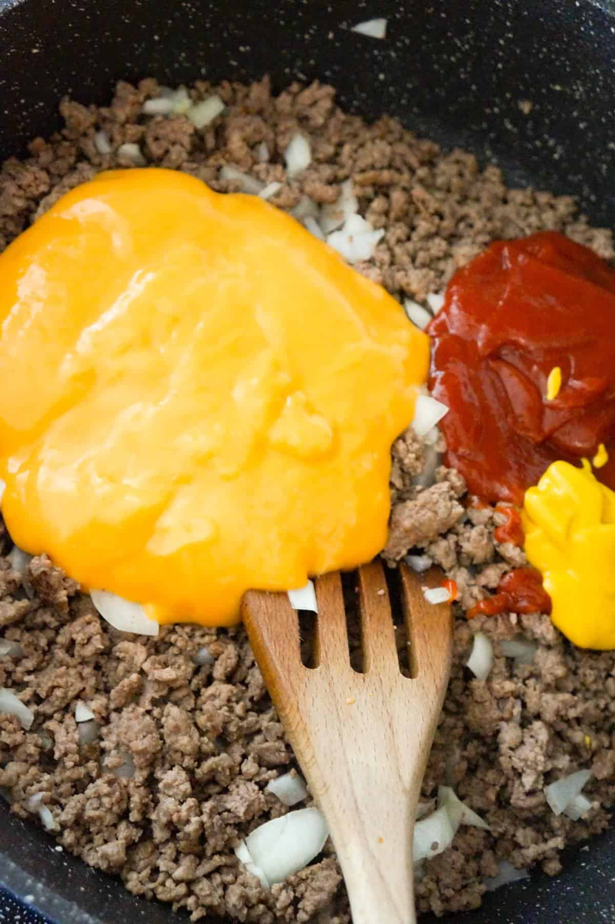 condensed cheddar cheese soup, ketchup and mustard on top of ground beef in a saute pan