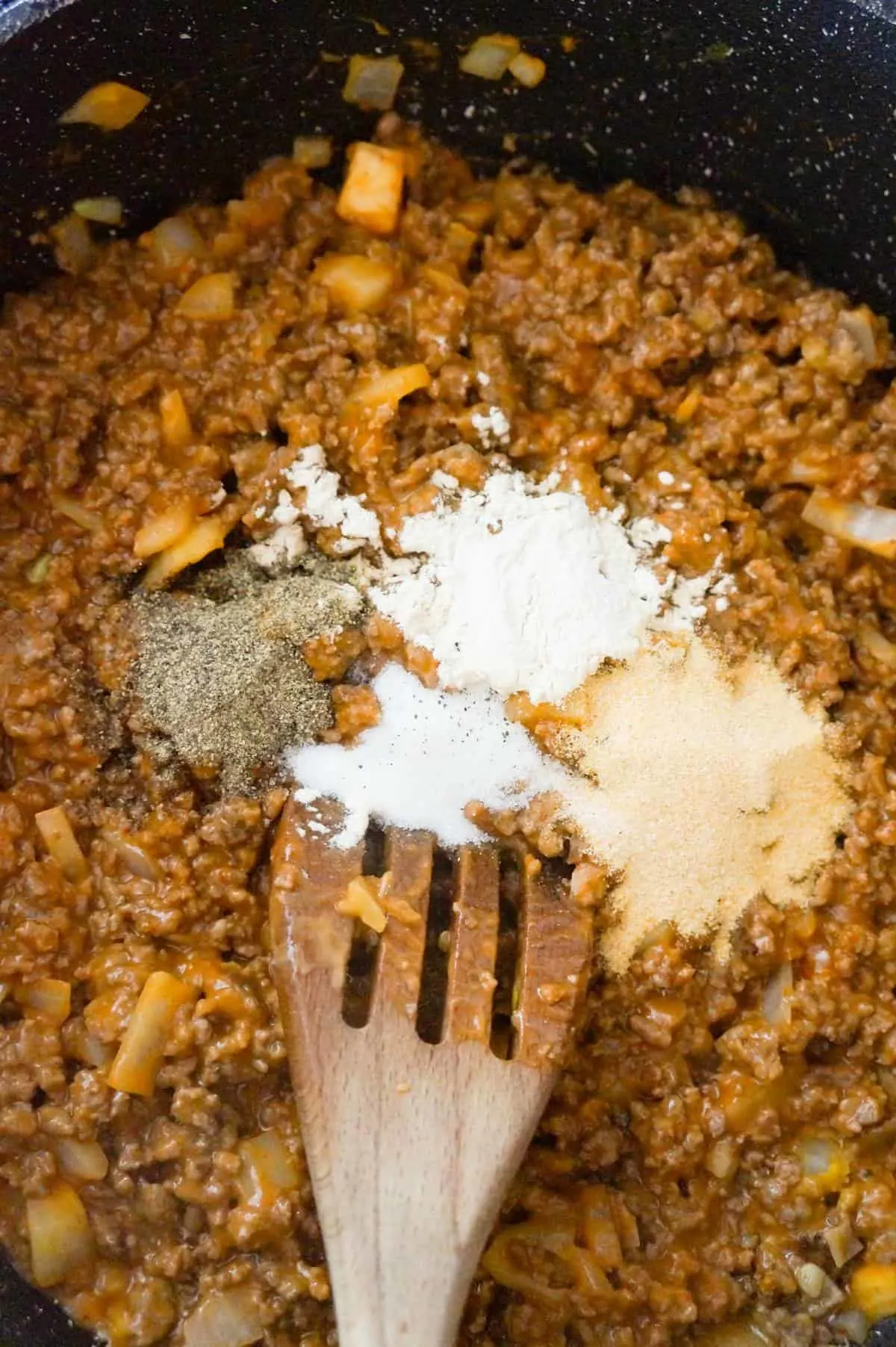 spices on top of ground beef mixture in a saute pan