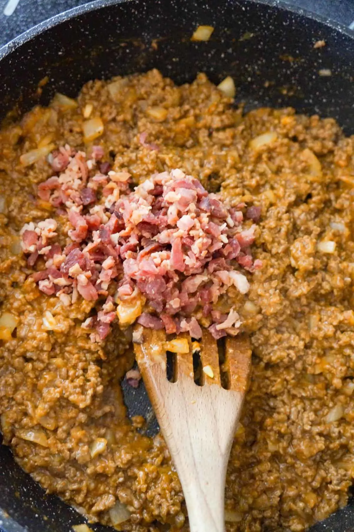 crumbled bacon on top of ground beef mixture in a saute pan