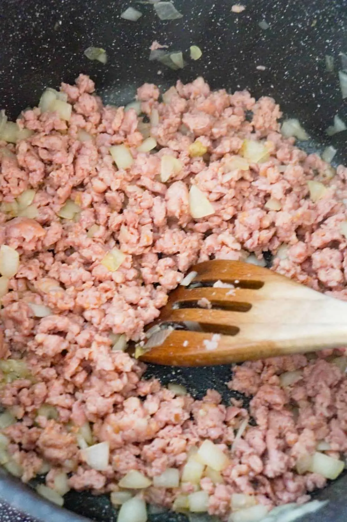ground sausage meat and diced onions cooking in a large pot