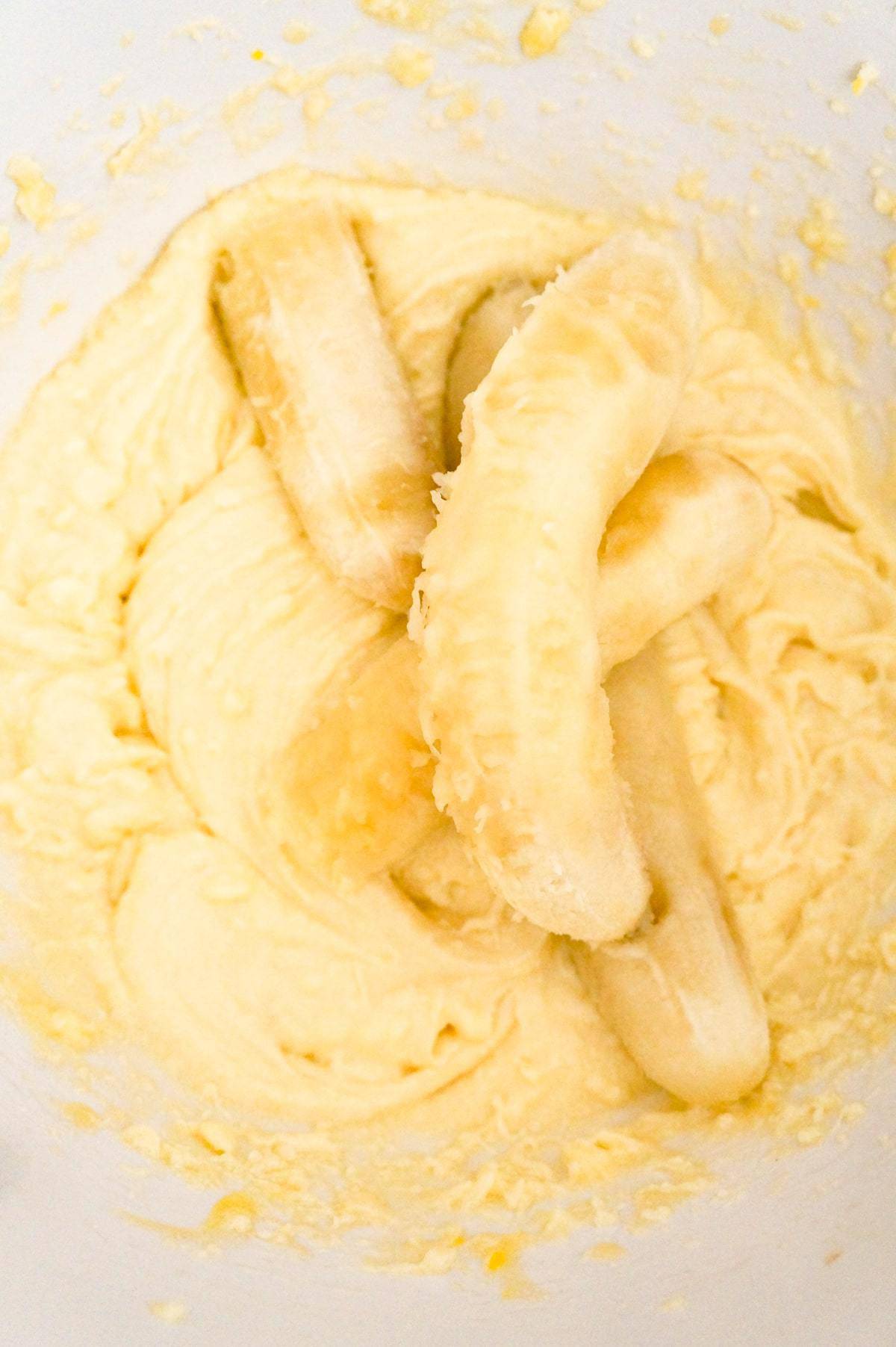 ripe bananas on top of creamy mixture in a mixing bolw