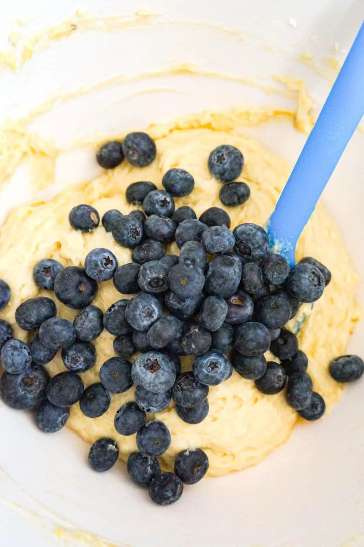 fresh blueberries on top of banana bread batter in a mixing bowl