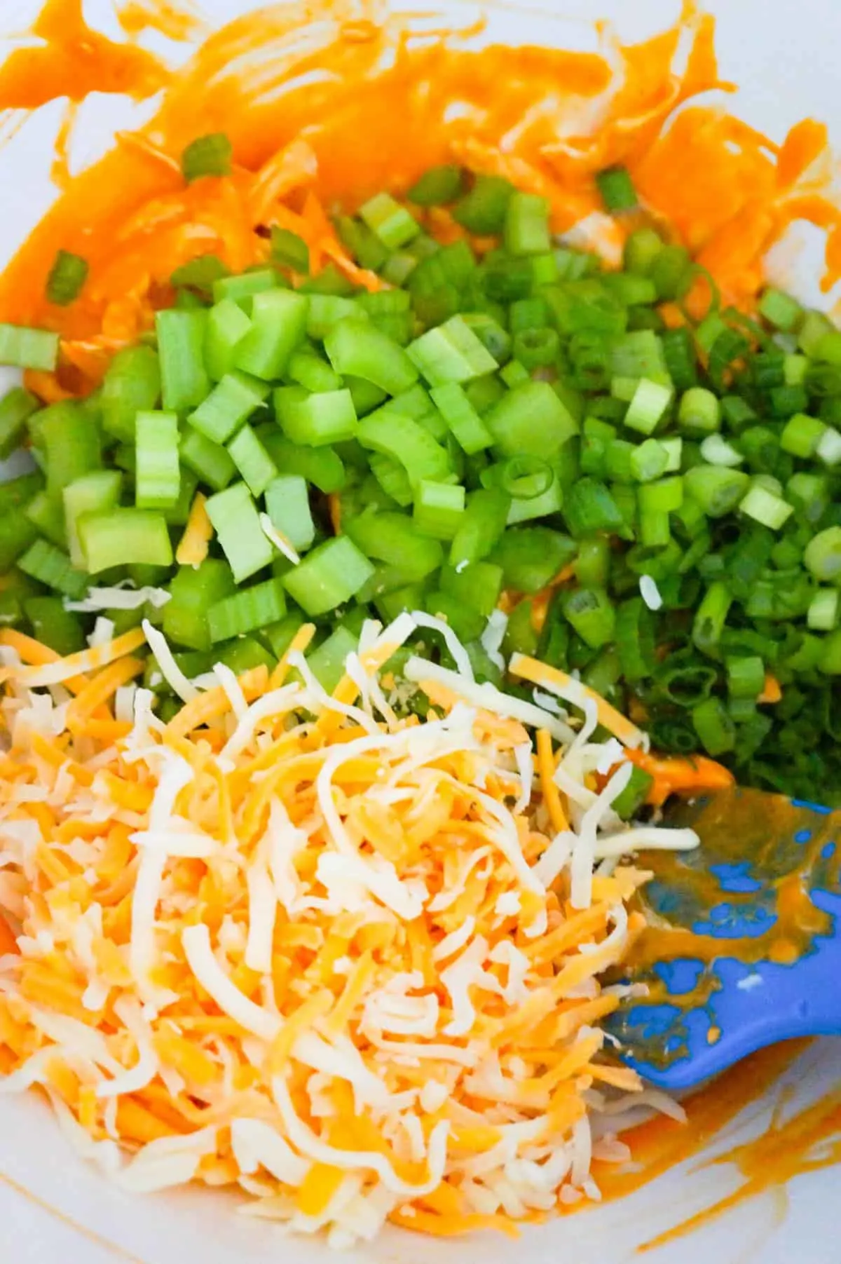diced celery, chopped green onions and shredded cheese in a mixing bowl