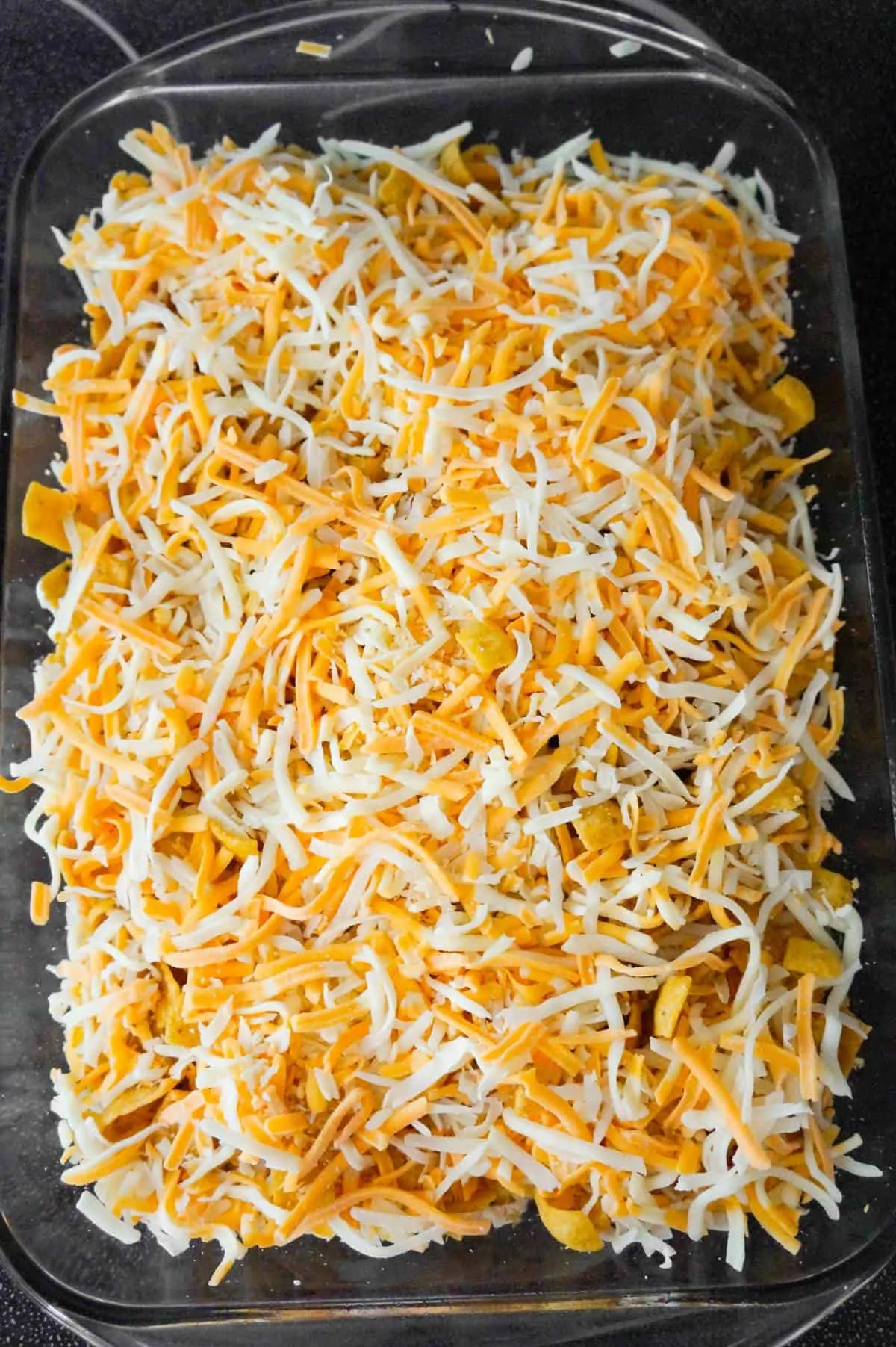 shredded mozzarella and cheddar cheese on top of buffalo chicken frito pie