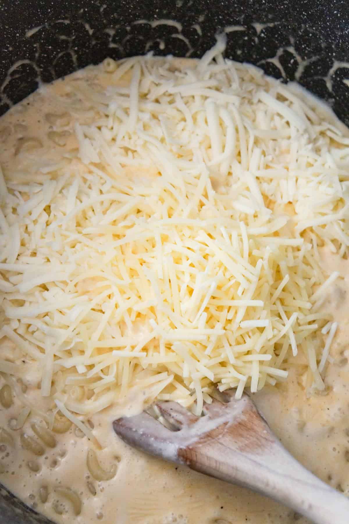 shredded Parmesan and mozzarella on top of creamy macaroni in a large pot