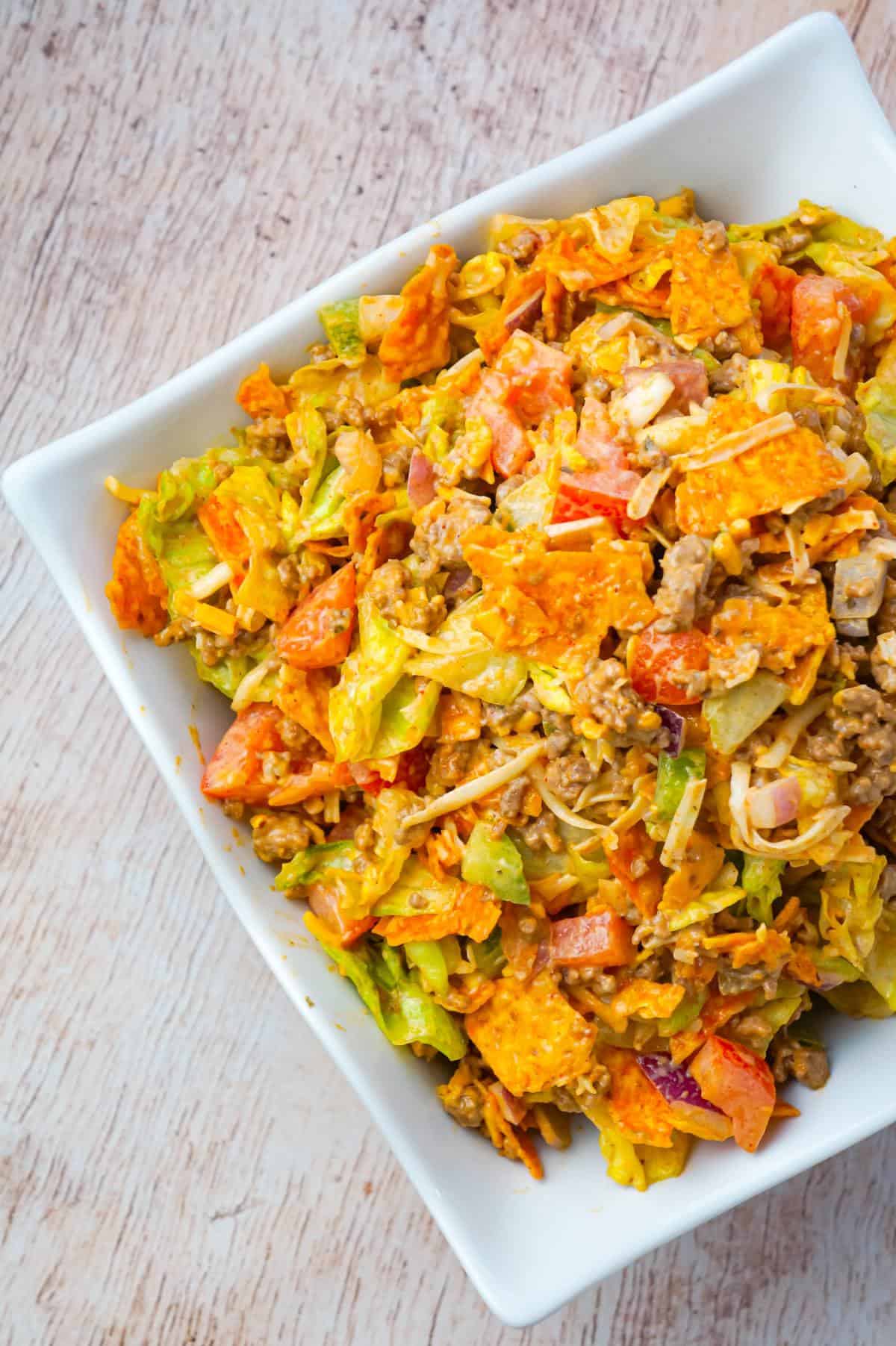 Doritos Taco Salad is a delicious salad loaded with iceberg lettuce, red onions, green peppers, tomatoes, shredded cheese, ground beef and crumbled Doritos all tossed in salsa and ranch dressing.