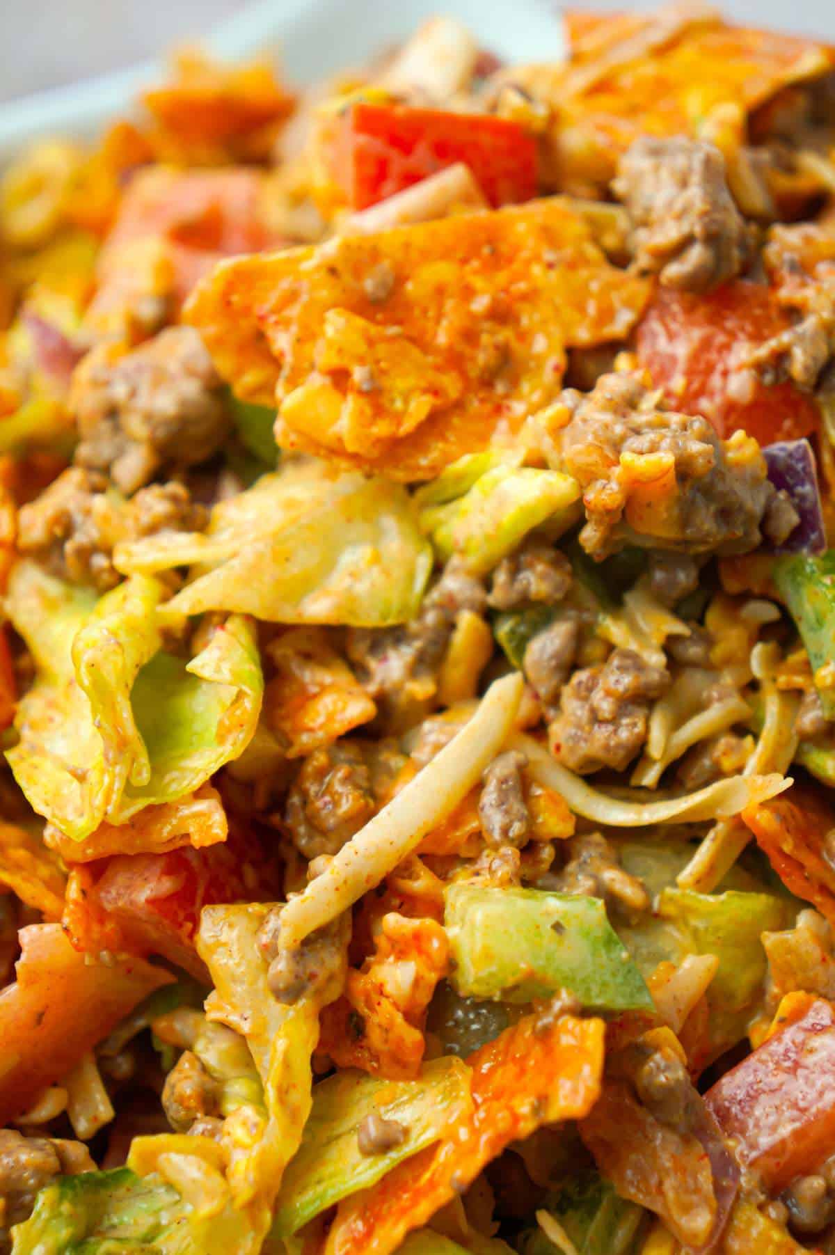 Doritos Taco Salad is a delicious salad loaded with iceberg lettuce, red onions, green peppers, tomatoes, shredded cheese, ground beef and crumbled Doritos all tossed in salsa and ranch dressing.