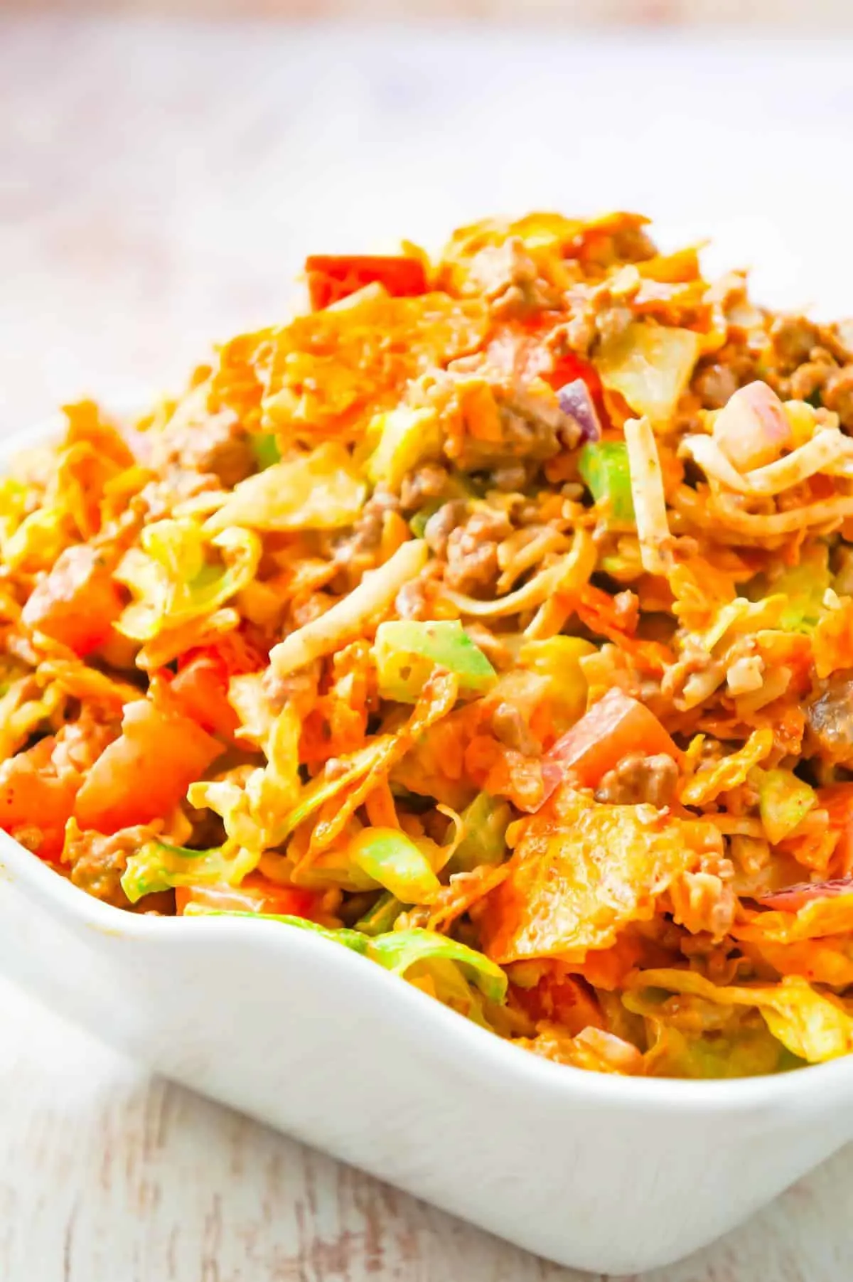 Doritos Taco Salad is a delicious salad loaded with iceberg lettuce, red onions, green peppers, tomatoes, shredded cheese, ground beef and crumbled Doritos all tossed in salsa and ranch dressing.