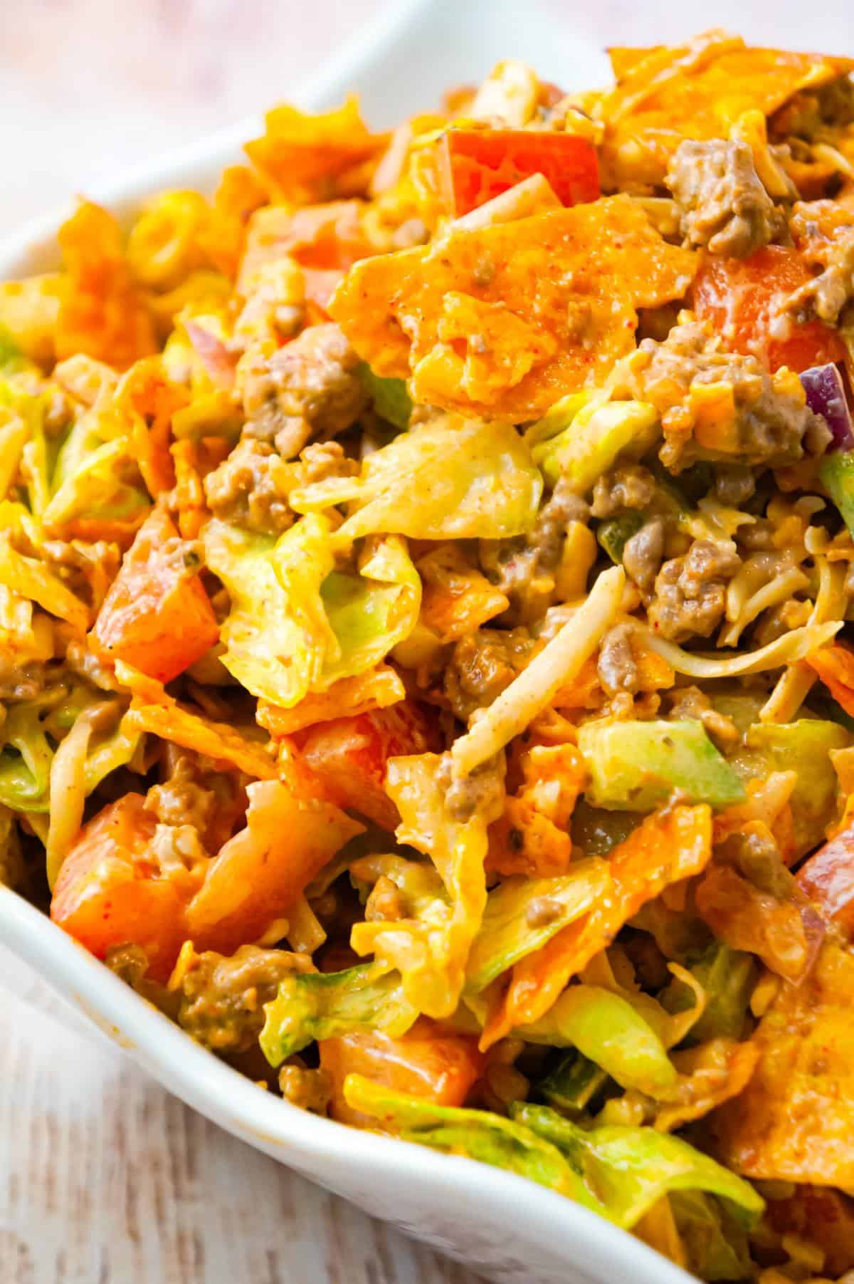 Doritos Taco Salad is a delicious salad loaded with iceberg lettuce, red onions, green peppers, tomatoes, shredded cheese, ground beef and crumbled Doritos all tossed in salsa and ranch dressing.