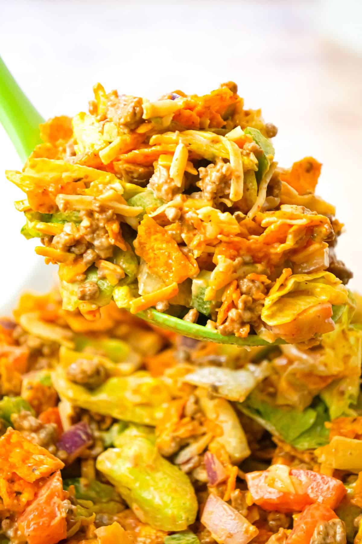 Doritos Taco Salad is a delicious salad loaded with iceberg lettuce, red onions, green peppers, tomatoes, shredded cheese, ground beef and crumbled Doritos all tossed in salsa and ranch dressing.