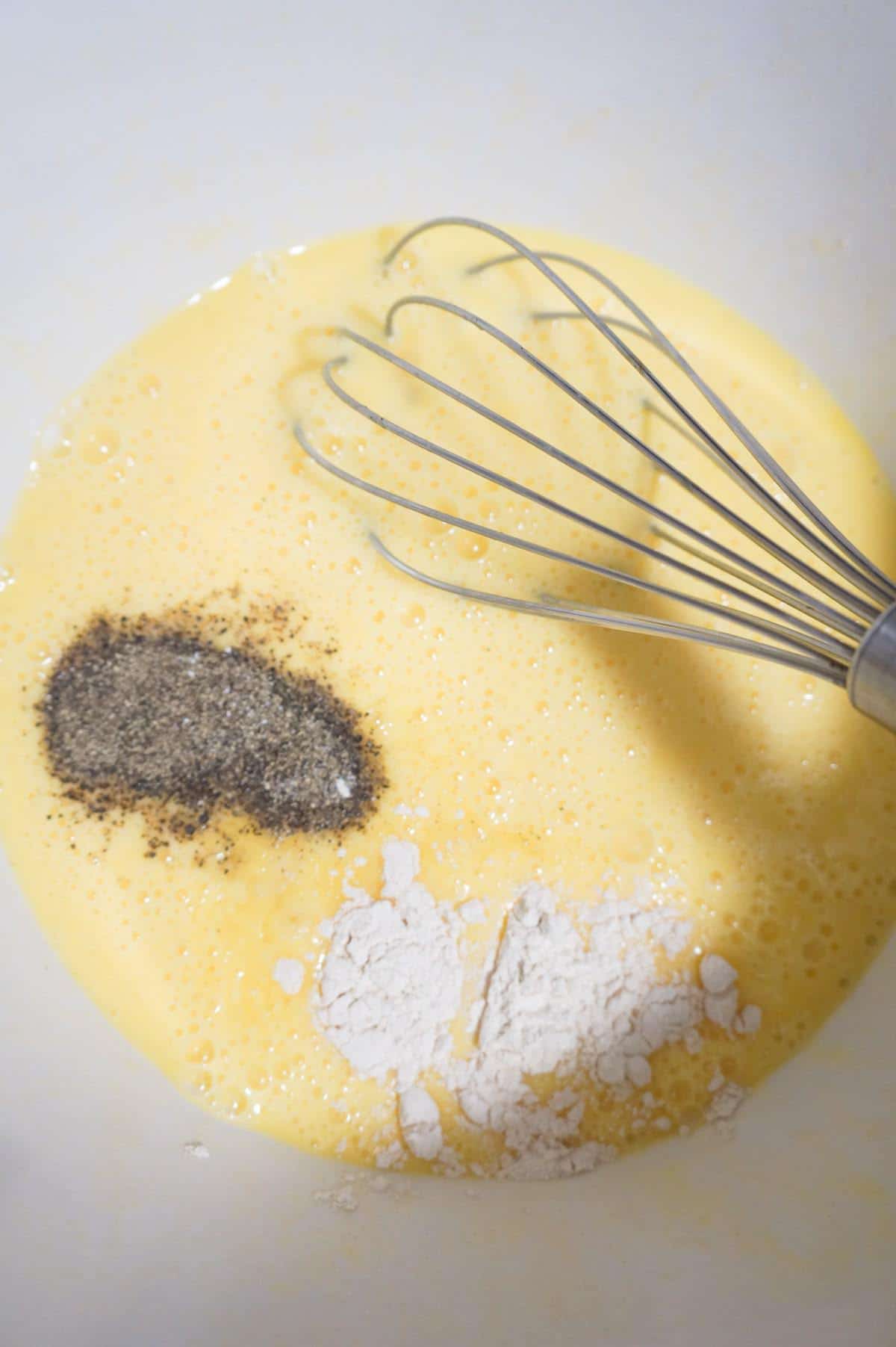 spices on top of beaten eggs in a mixing bowl