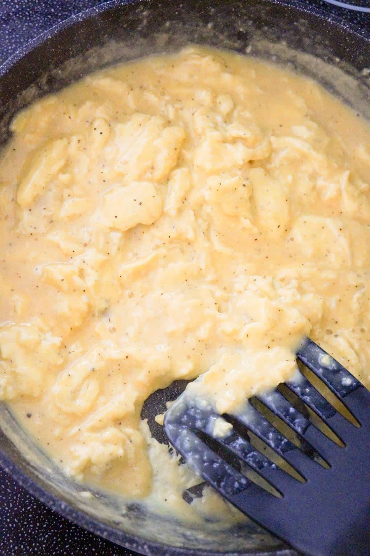 scrambled eggs cooking in a saute pan