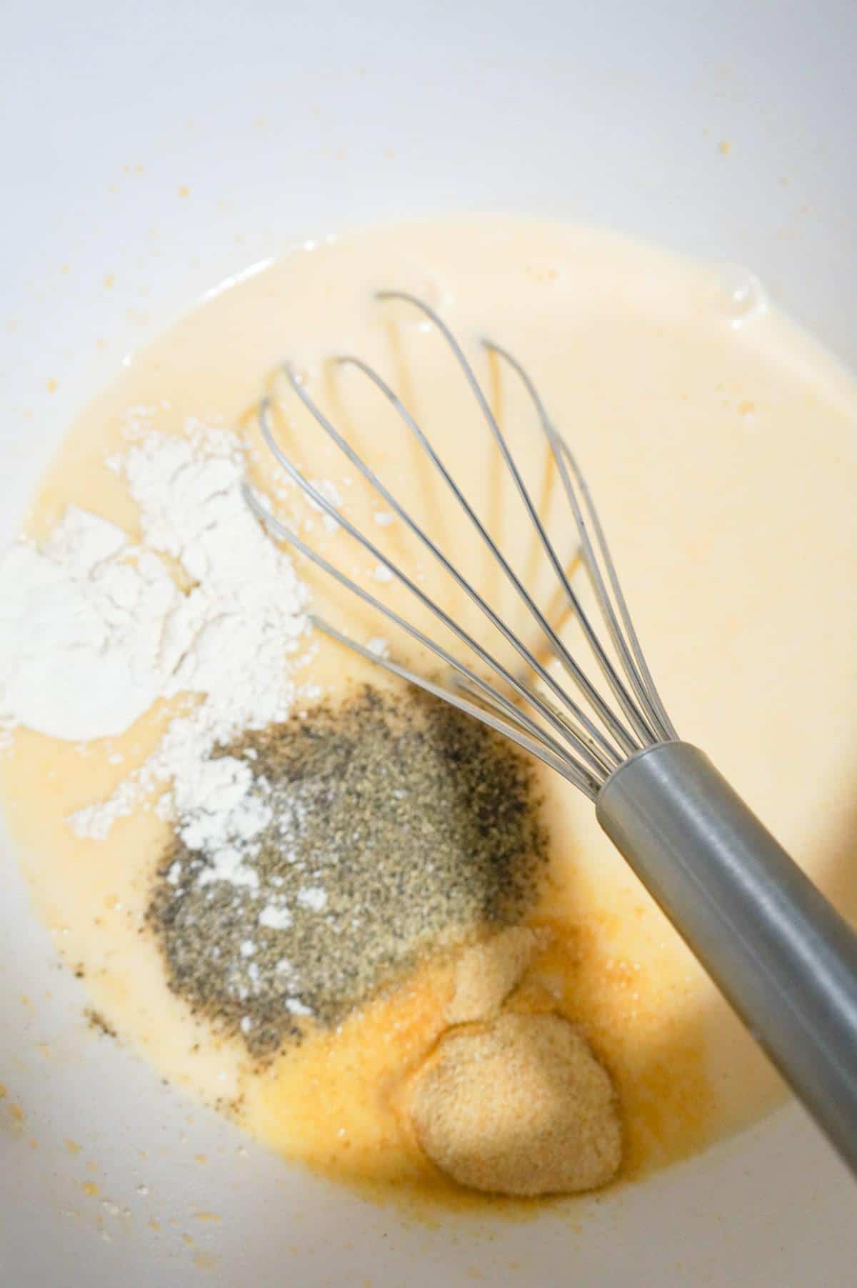 spices on top of milk and cheddar soup mixture in a mixing bowl