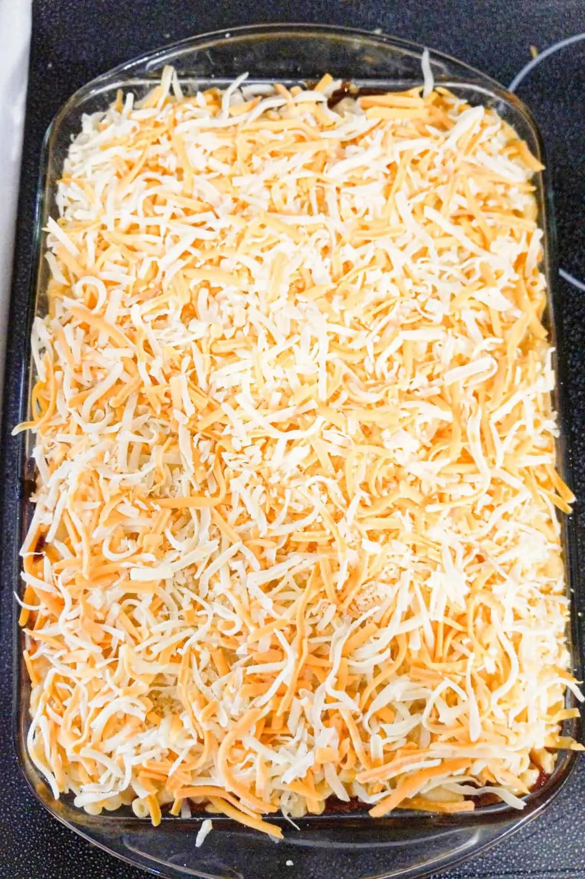 shredded cheese on top of macaroni in a baking dish