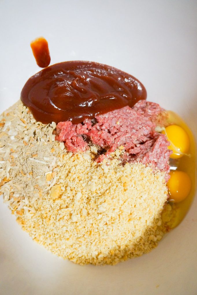 ketchup and bbq sauce mixture, Ritz cracker crumbs, onion soup mix, eggs and ground beef in a mixing bowl