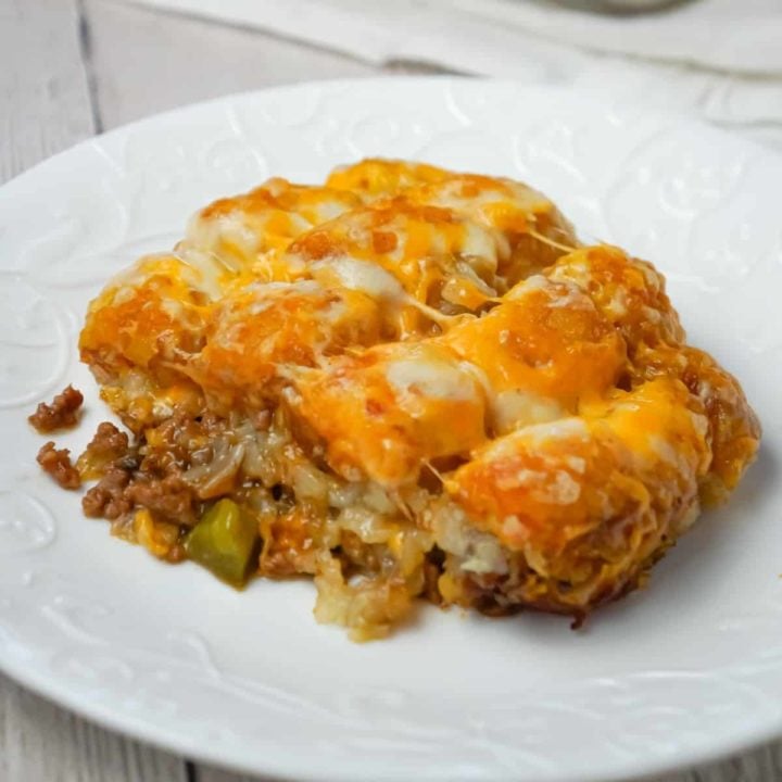 Philly Cheese Steak Tater Tot Casserole is a hearty dinner recipe with a base of ground beef, diced onion, diced green peppers and sliced mushrooms tossed in brown gravy and topped with shredded cheese and tater tots.