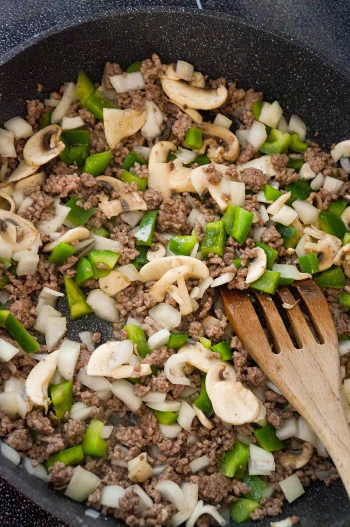 sliced mushrooms, diced green peppers and ground beef cooking in a saute pan