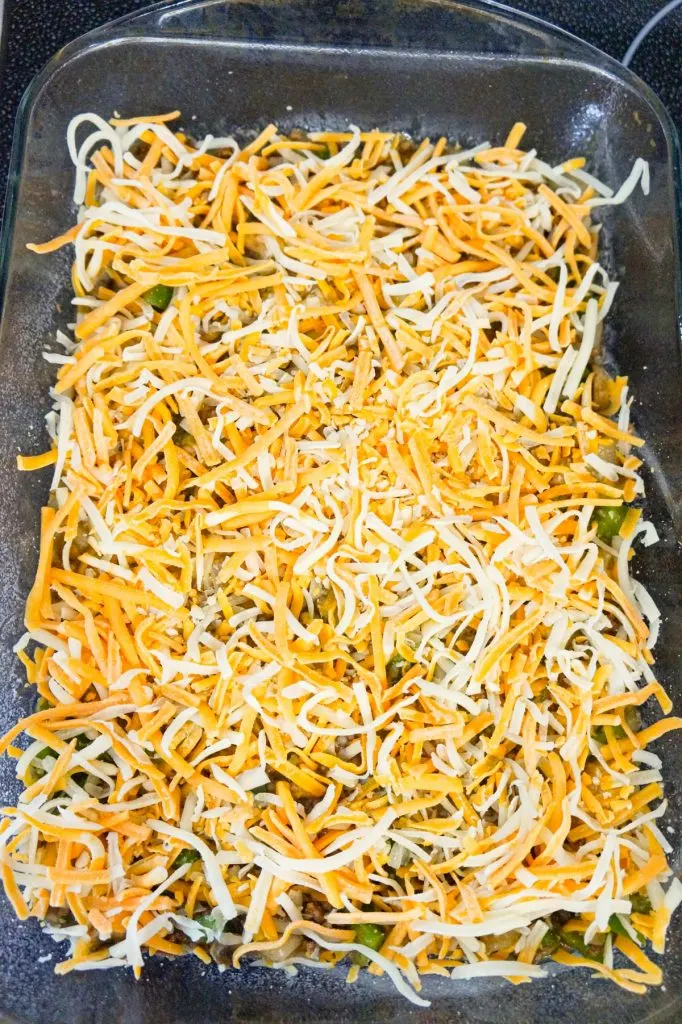 shredded cheese on top of ground beef mixture in a baking dish