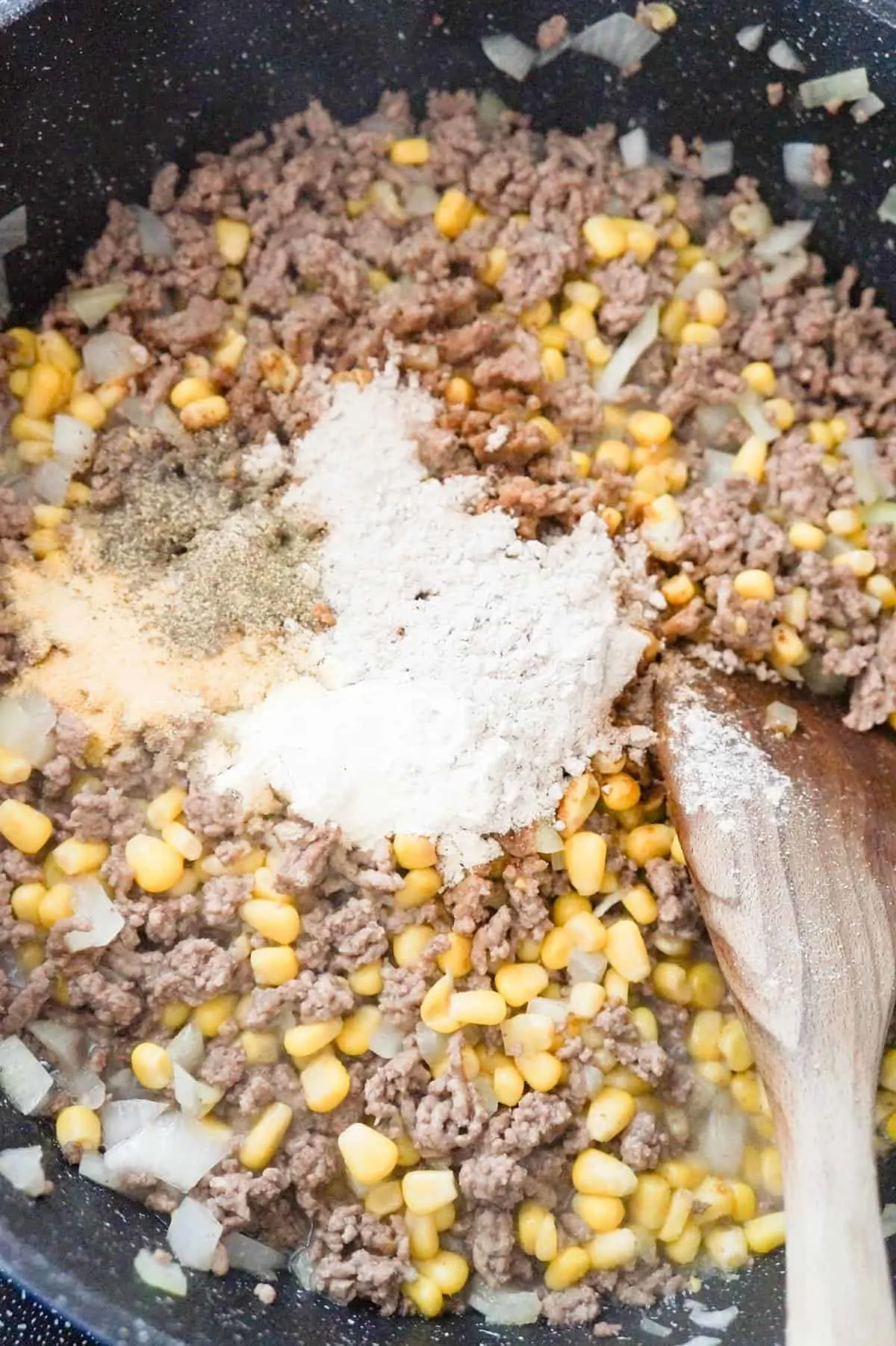 gravy mix and spices on top of ground beef and corn mixture in a saute pan