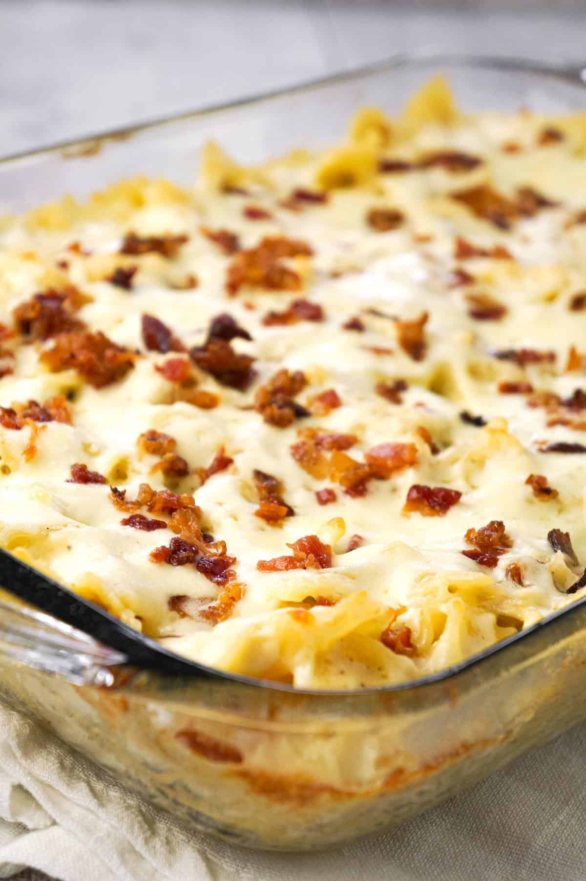 Baked Chicken Alfredo Pasta with Bacon is a delicious dinner recipe loaded with bow tie pasta, shredded chicken and crumbled bacon all in a creamy garlic Parmesan sauce and baked with mozzarella on top.