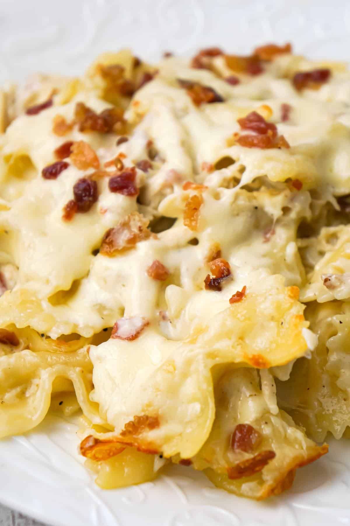 Baked Chicken Alfredo Pasta with Bacon is a delicious dinner recipe loaded with bow tie pasta, shredded chicken and crumbled bacon all in a creamy garlic Parmesan sauce and baked with mozzarella on top.