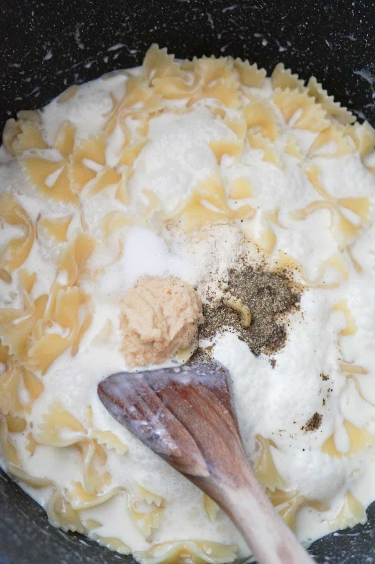 spices on top of creamy bow tie pasta in a large pot