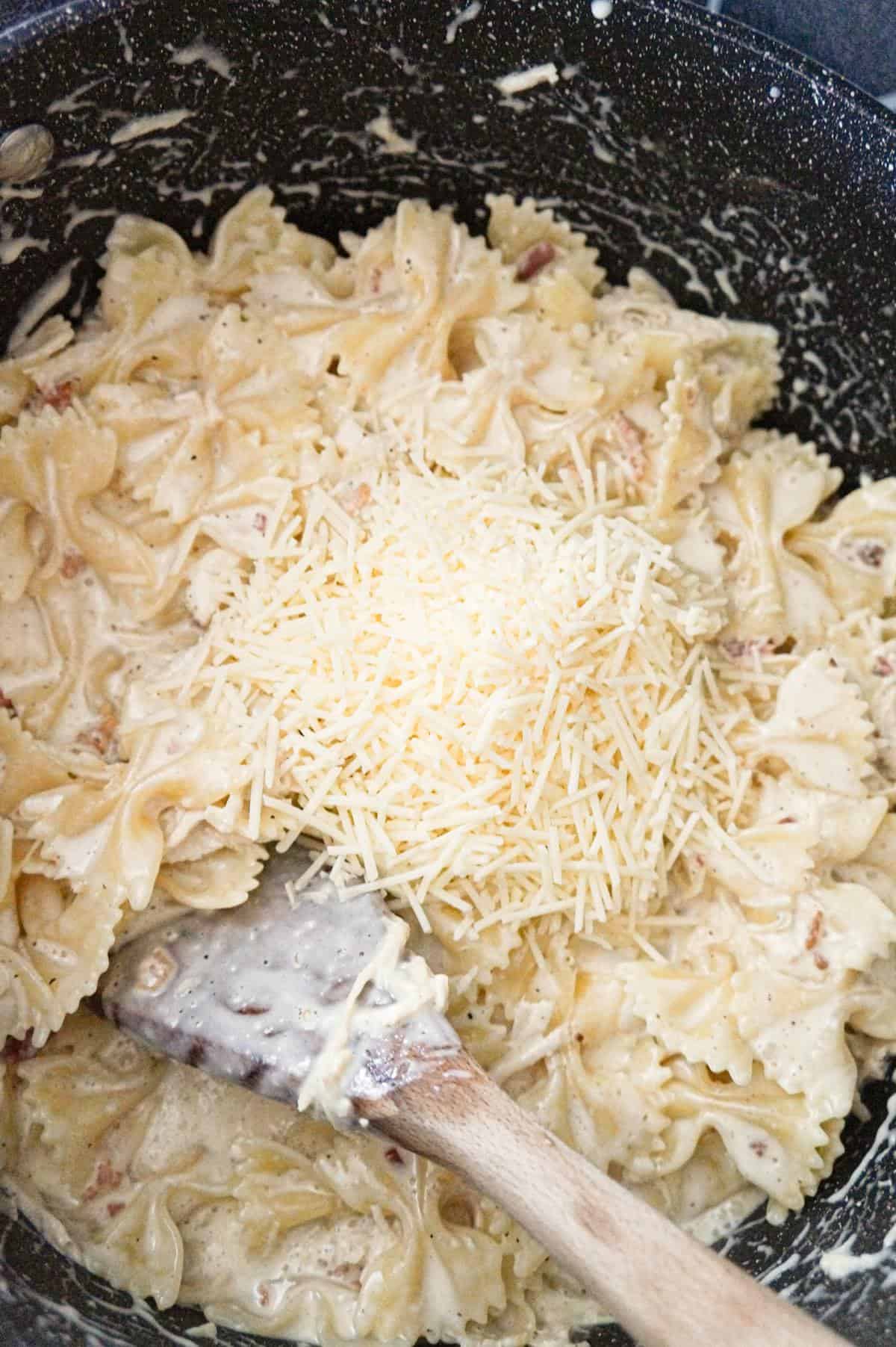 shredded Parmesan cheese on top of bow tie pasta in a large pot