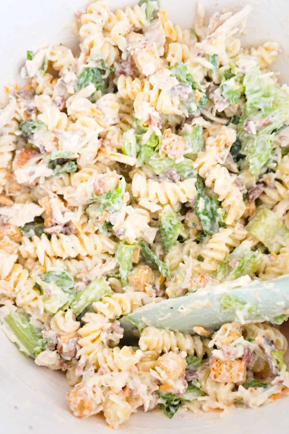 chicken caesar pasta salad in a mixing bowl