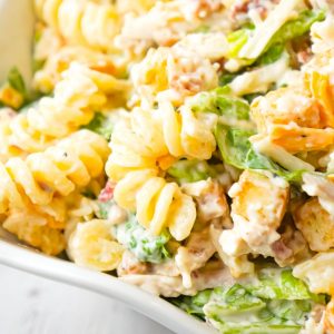 Chicken Caesar Pasta Salad is a tasty side cold dish recipe loaded with chopped romaine, shredded chicken, crumbled bacon, croutons, shredded mozzarella, cheddar and Parmesan cheese all tossed in a creamy garlic Parmesan dressing.