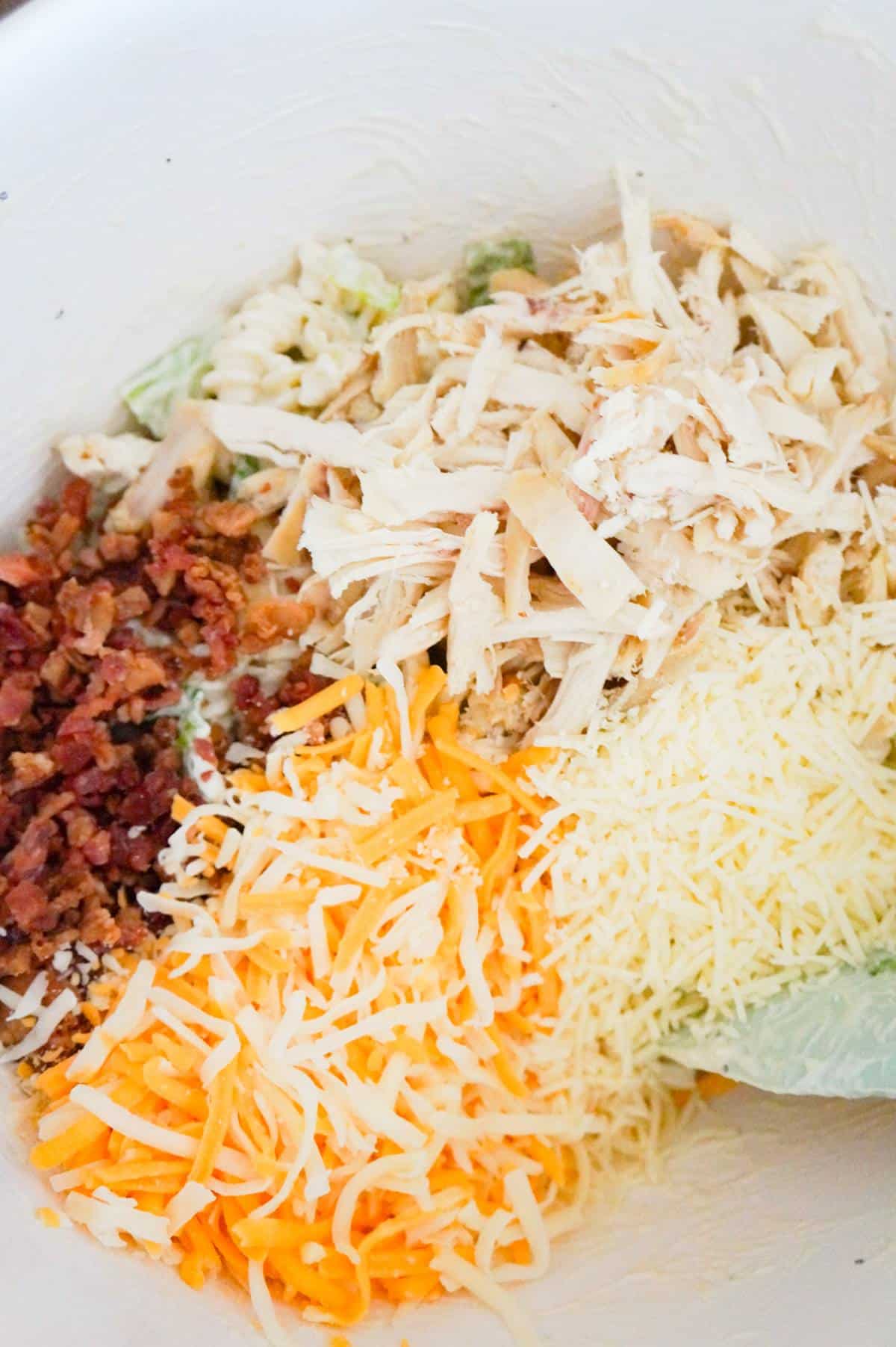 shredded chicken, crumbled bacon, shredded mozzarella, cheddar and Parmesan in a mixing bowl