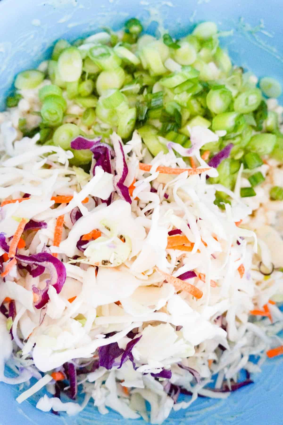 shredded coleslaw mix and chopped green onions in a mixing bowl