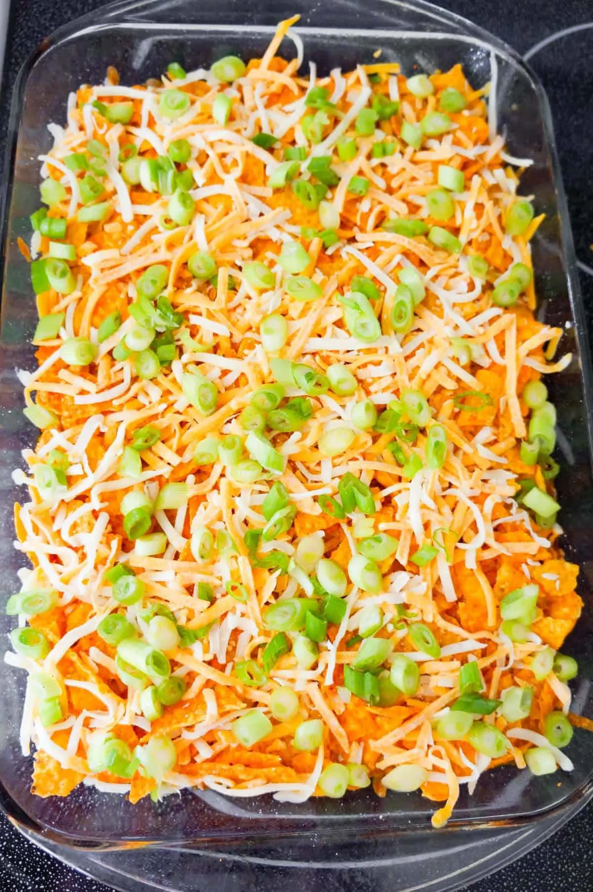 chopped green onions and shredded cheese on top of Doritos Chili Pie