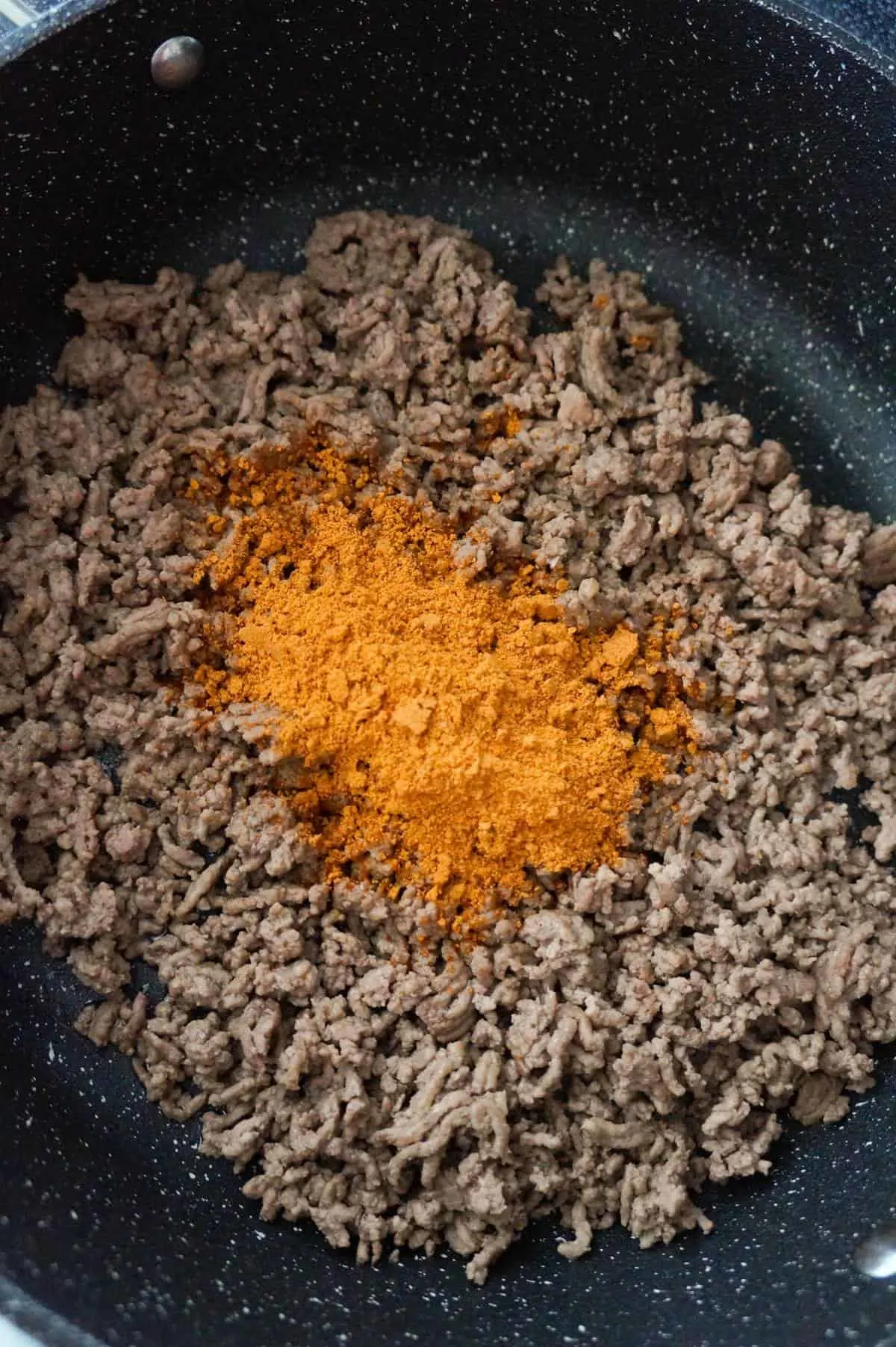 chili seasoning on top of cooked ground beef in a saute pan