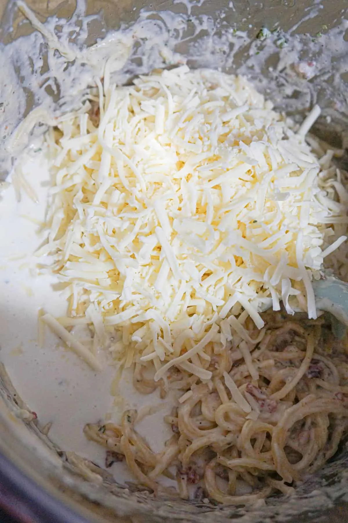 shredded cheese and heavy cream on top of spaghetti in an Instant Pot