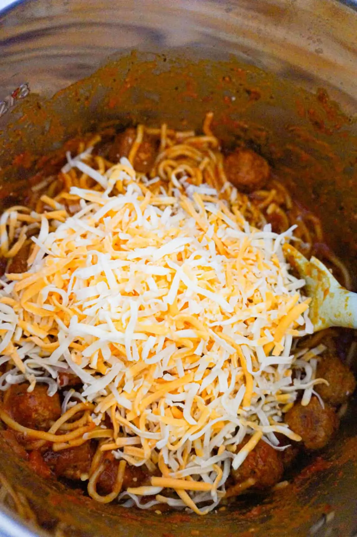 shredded mozzarella and cheddar cheese on top of spaghetti and meatballs in an Instant Pot
