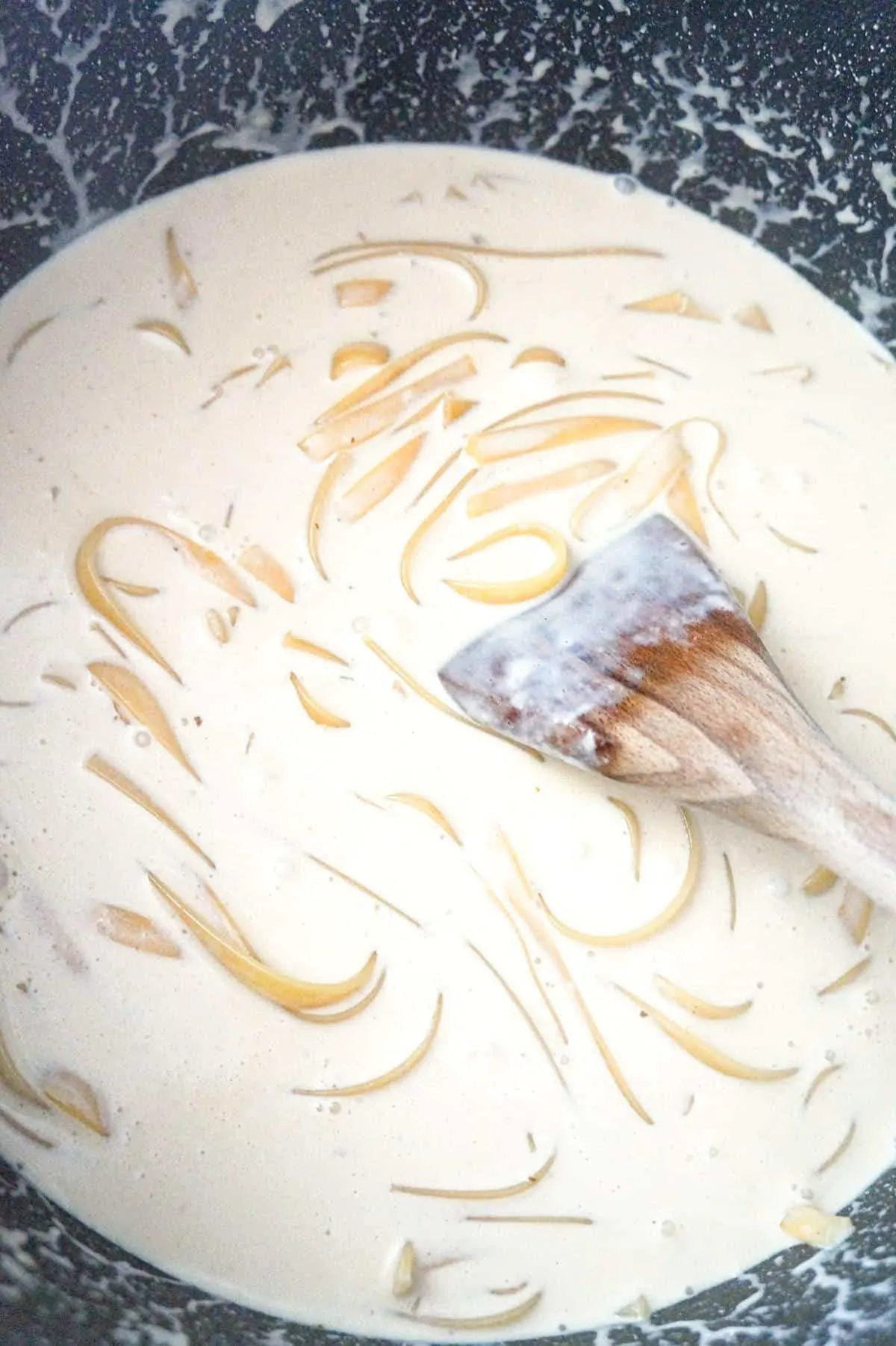 fettuccine cooking in a large pot with heavy cream