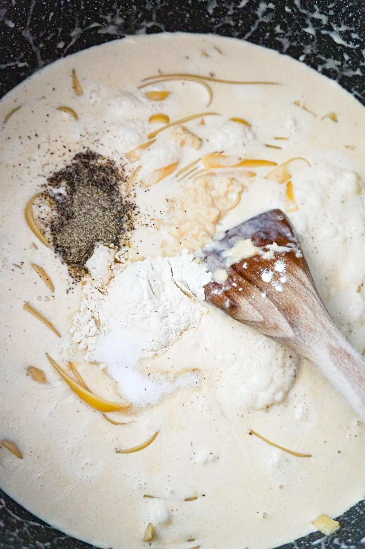 spices on top of fettuccine and heavy cream in a large pot
