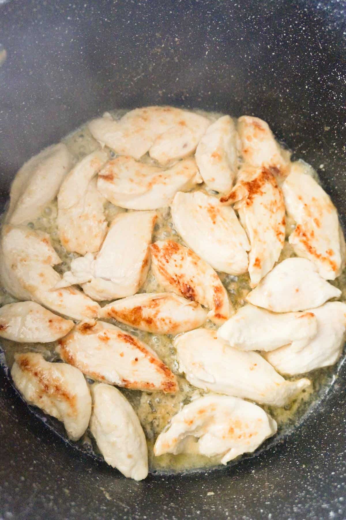 chicken breast slices cooking in butter in a large pot